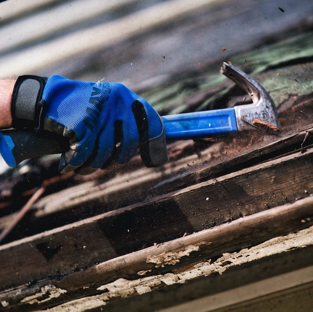 person holding a hammer and working with roof